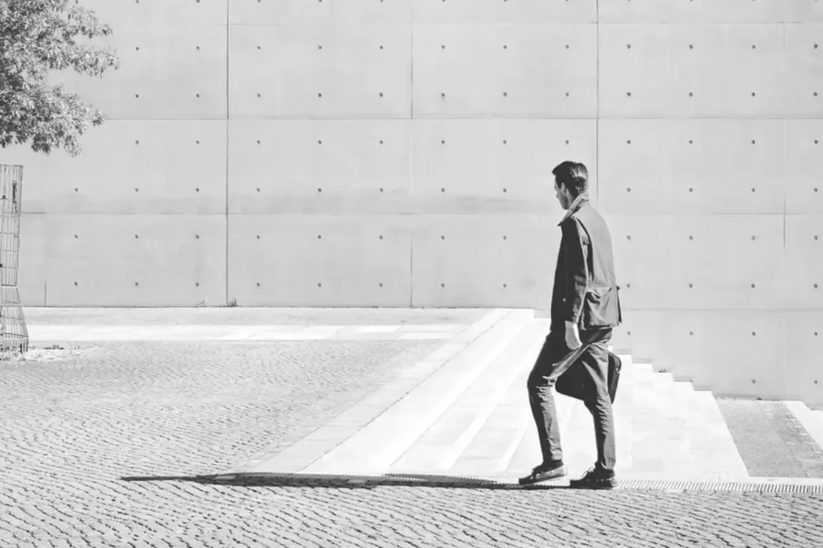 Un hombre de traje camina junto a un muro de hormigón